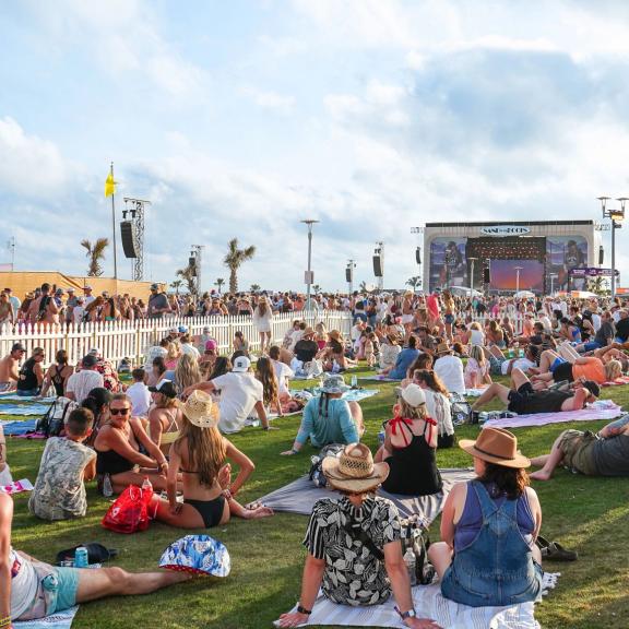 Crowd relaxing on blankets in the grass during Hangout Music Fest in Gulf Shores
